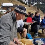 Austrian man cutting cheese for students to try 