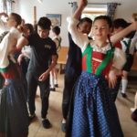 A group of boys and girls in traditional Austrian outfits dancing