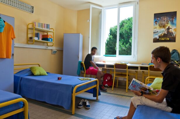 2 teenage boys sitting in a shared bedroom